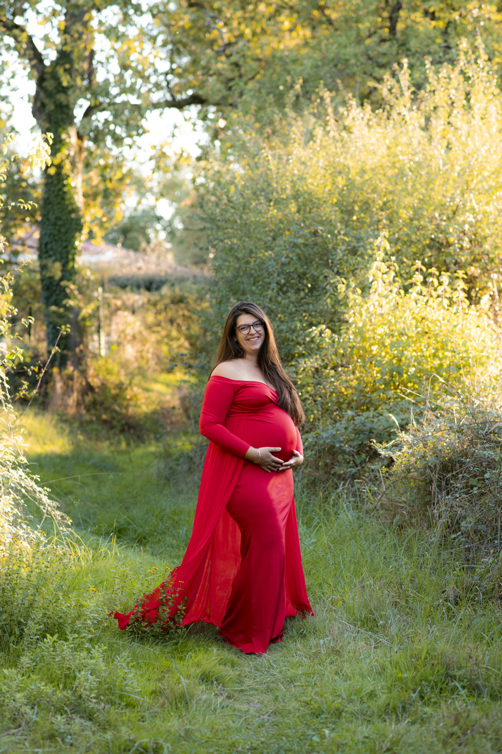 femme enceinte souriante ayant une robe rouge dans une espace vert